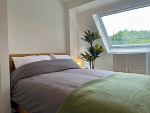 Quarto com cama, janela, planta e guarda-roupa.