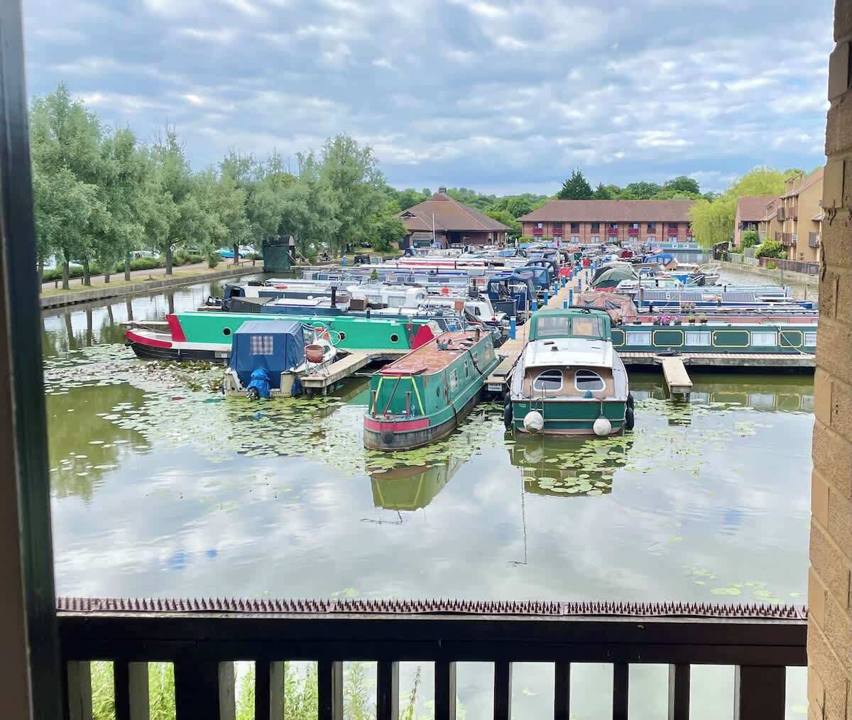 A canal with boats docked, surrounded by trees and buildings.