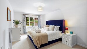A bedroom with a bed, bedside tables, a lamp, and a window with curtains.
