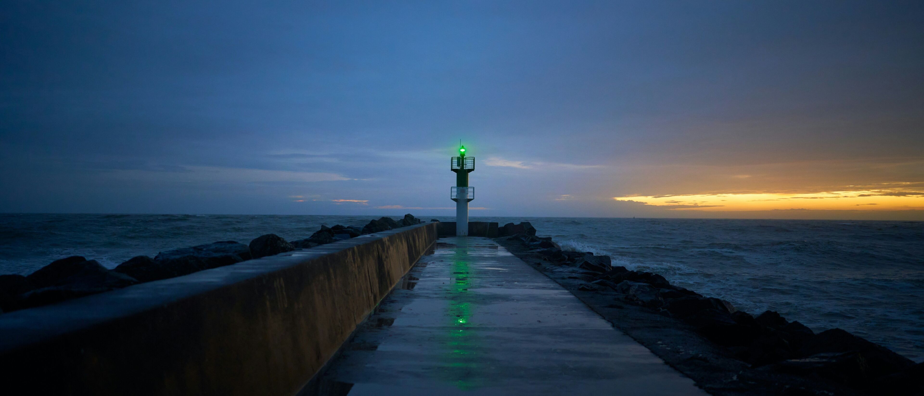 A pier extending into the sea with a lighthouse at the end.