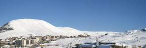 Ein schneebedeckter Berg mit einem Skigebiet und Gebäuden am Fuße.