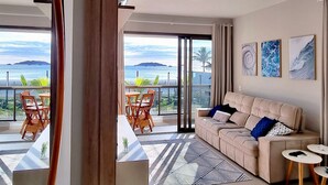 Ett modernt vardagsrum med en soffa, ett soffbord och utsikt över havet.