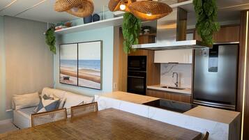 Una cocina moderna con refrigerador incorporado, microondas y pileta. Hay un comedor con mesa y sillas de madera.