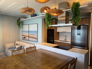 Una cocina moderna con refrigerador incorporado, microondas y pileta. Hay un comedor con mesa y sillas de madera.