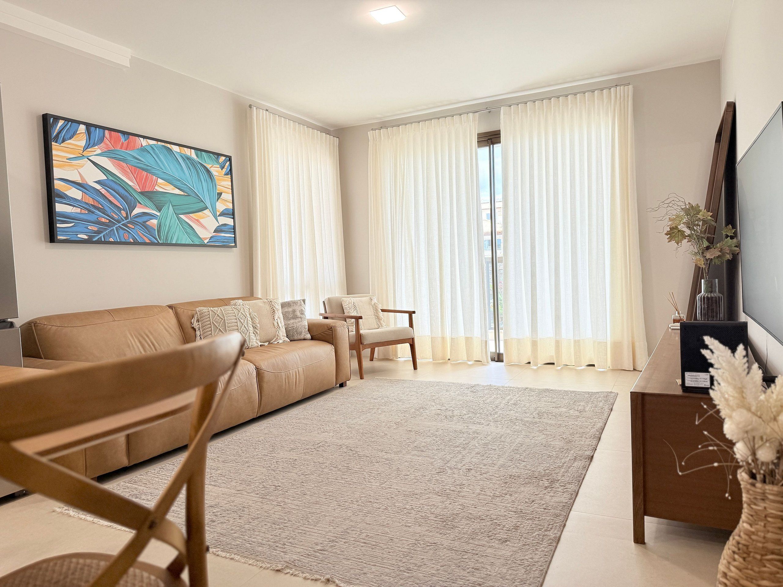 Una sala de estar con sofá, sillón, mesa de centro y televisor.