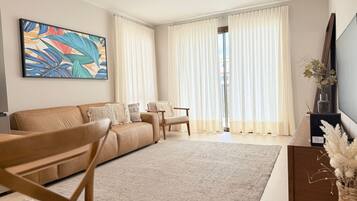 Una sala de estar con sofá, sillón, mesa de centro y televisor.