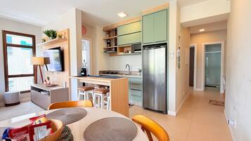 A modern kitchen with a built-in refrigerator, a dining area with a table and chairs, and a view of the city through a large window.