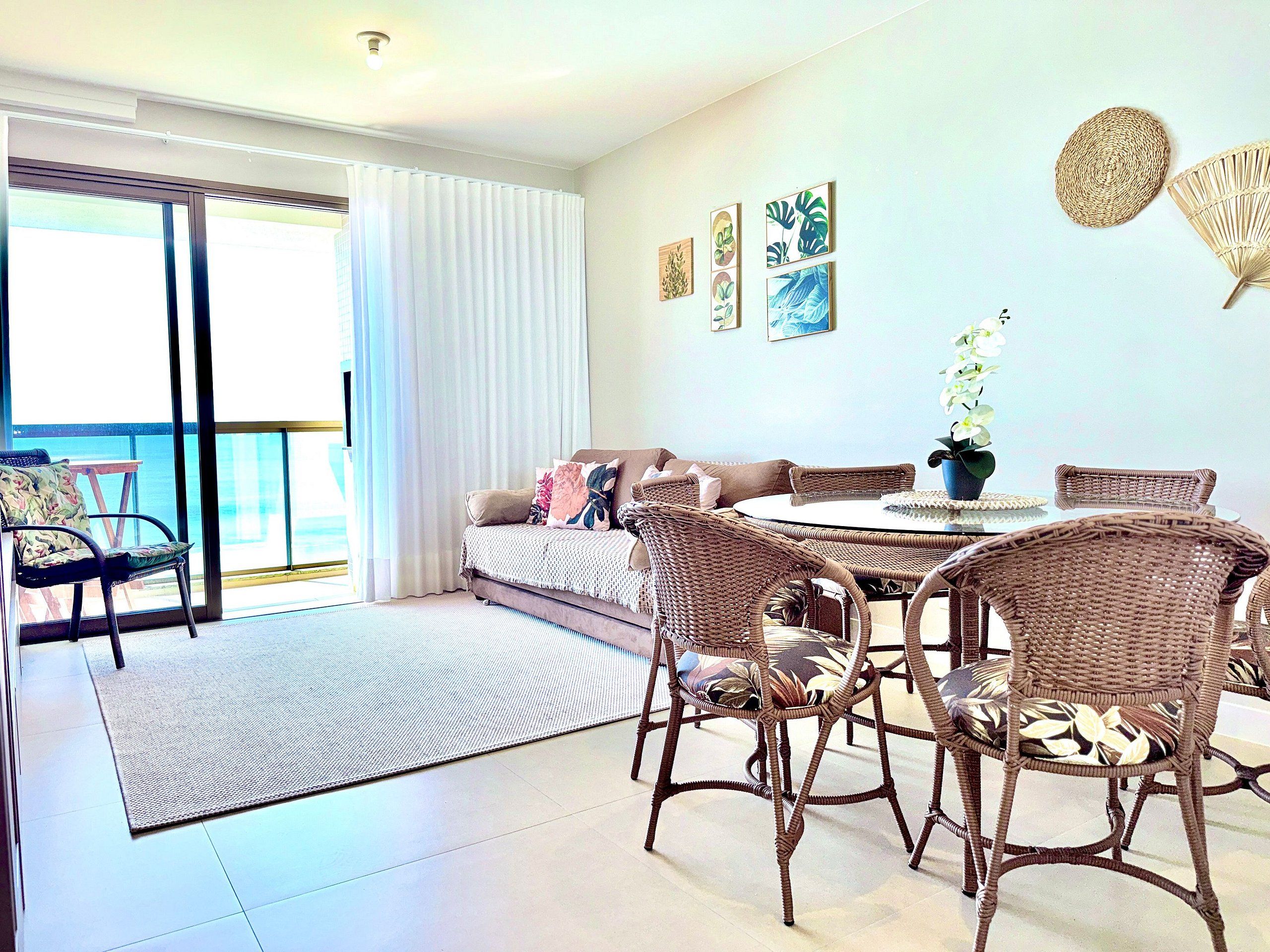 A room with a balcony, wicker furniture, a round table, and wall art.