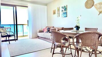 A room with a balcony, wicker furniture, a round table, and wall art.