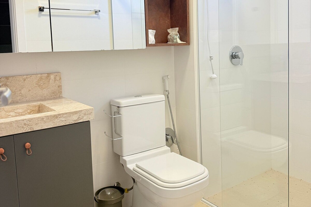 Une salle de bain moderne équipée de toilettes, d’une douche et d’un plan de toilette en marbre.