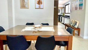 A dining area with a rectangular table, six chairs, and two wall-mounted paintings.