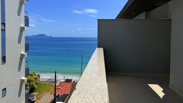 A balcony with a view of the sea and a building with tiled walls.