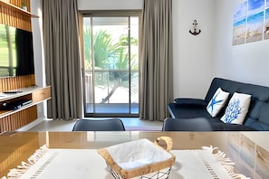 Una sala de estar moderna con televisor, sofá y zona de comedor.