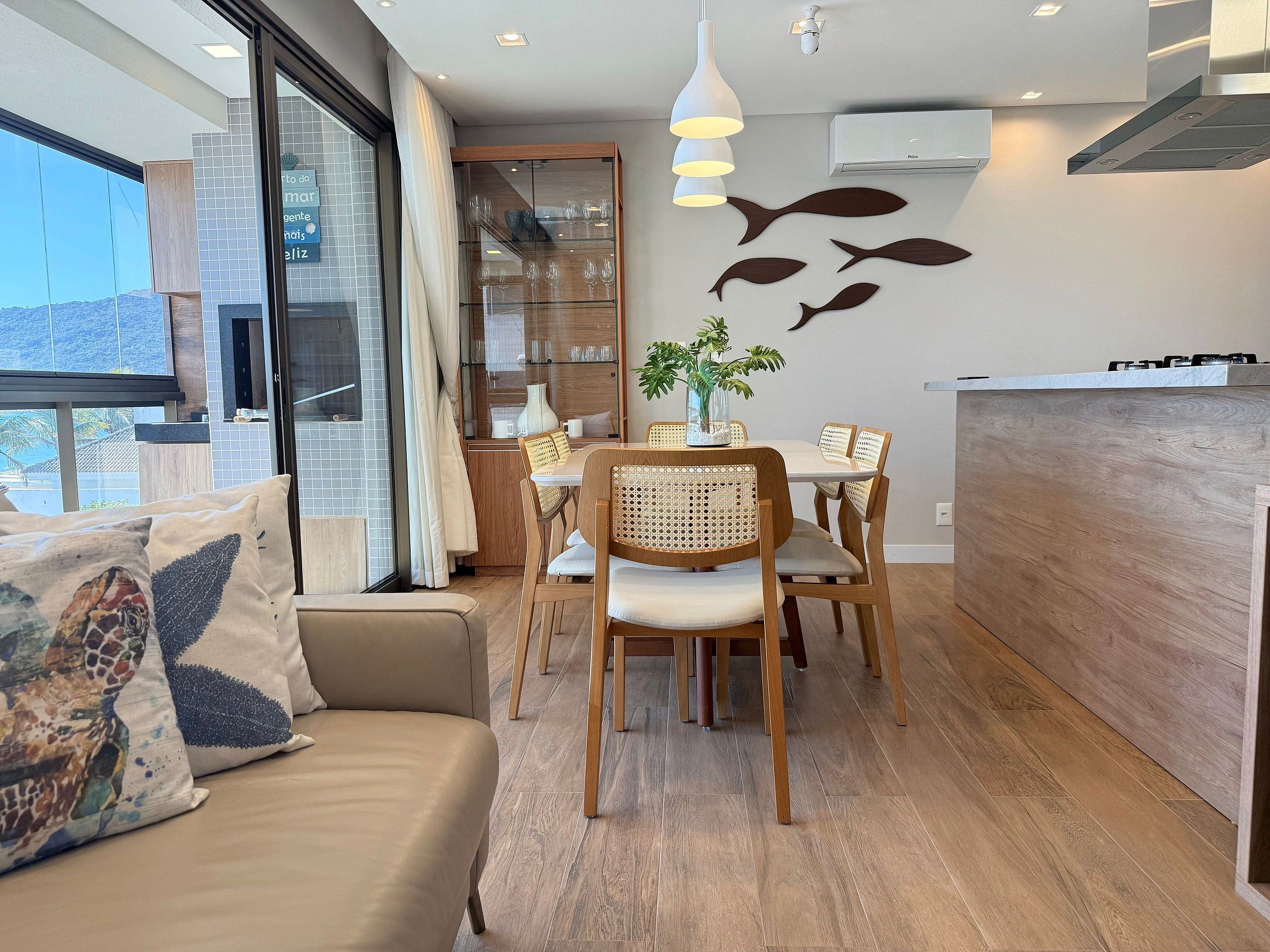 Una cocina moderna con zona de comedor, piso de madera y vistas amplias a través de grandes ventanales.