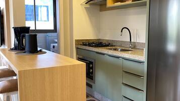 Una cocina moderna con una isla de madera, electrodomésticos de acero inoxidable y un ventanal con persianas.