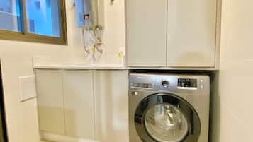 A compact laundry room with a front-loading washing machine and a water heater.