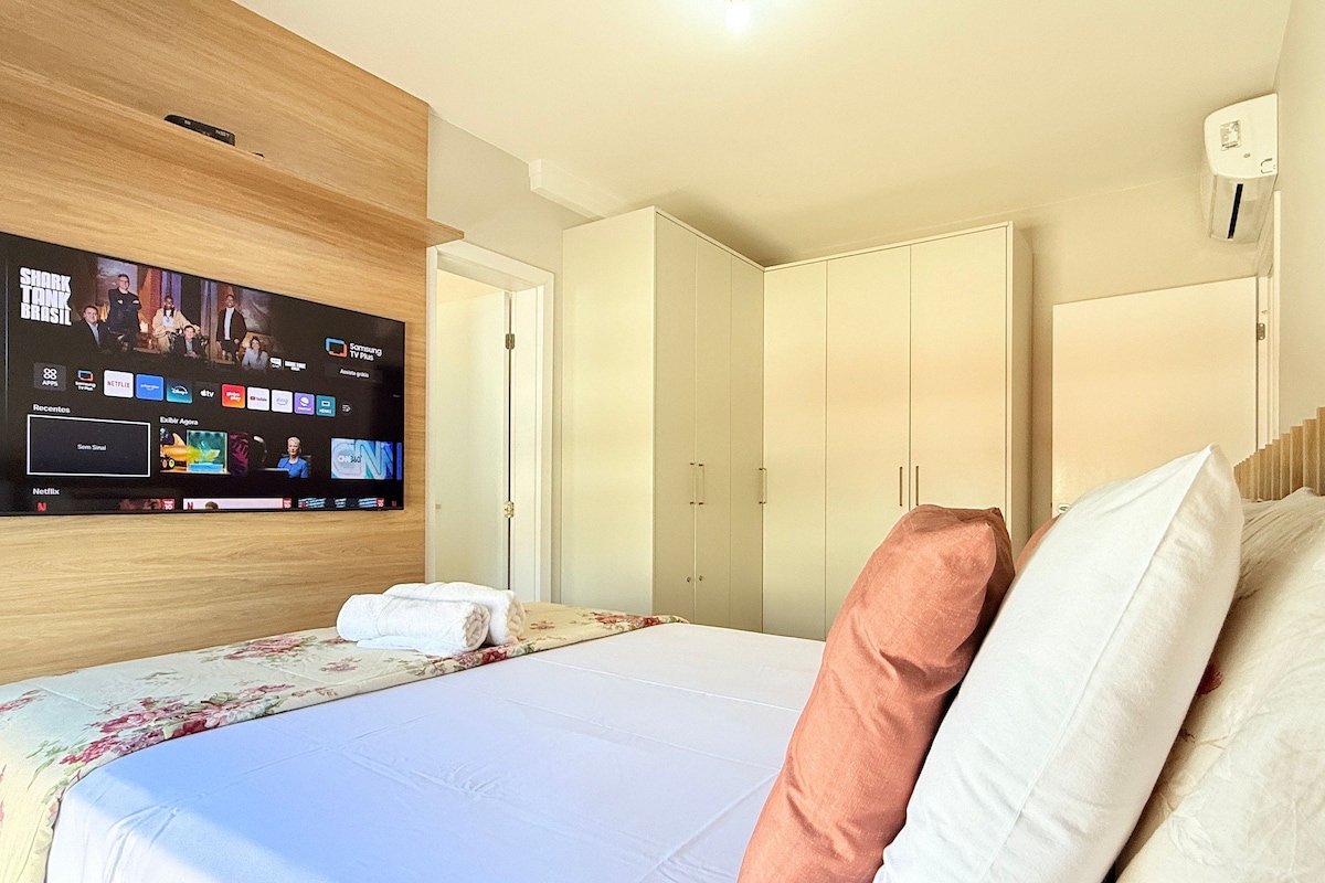Une chambre d’hôtel avec un lit, un téléviseur fixé au mur et une armoire.