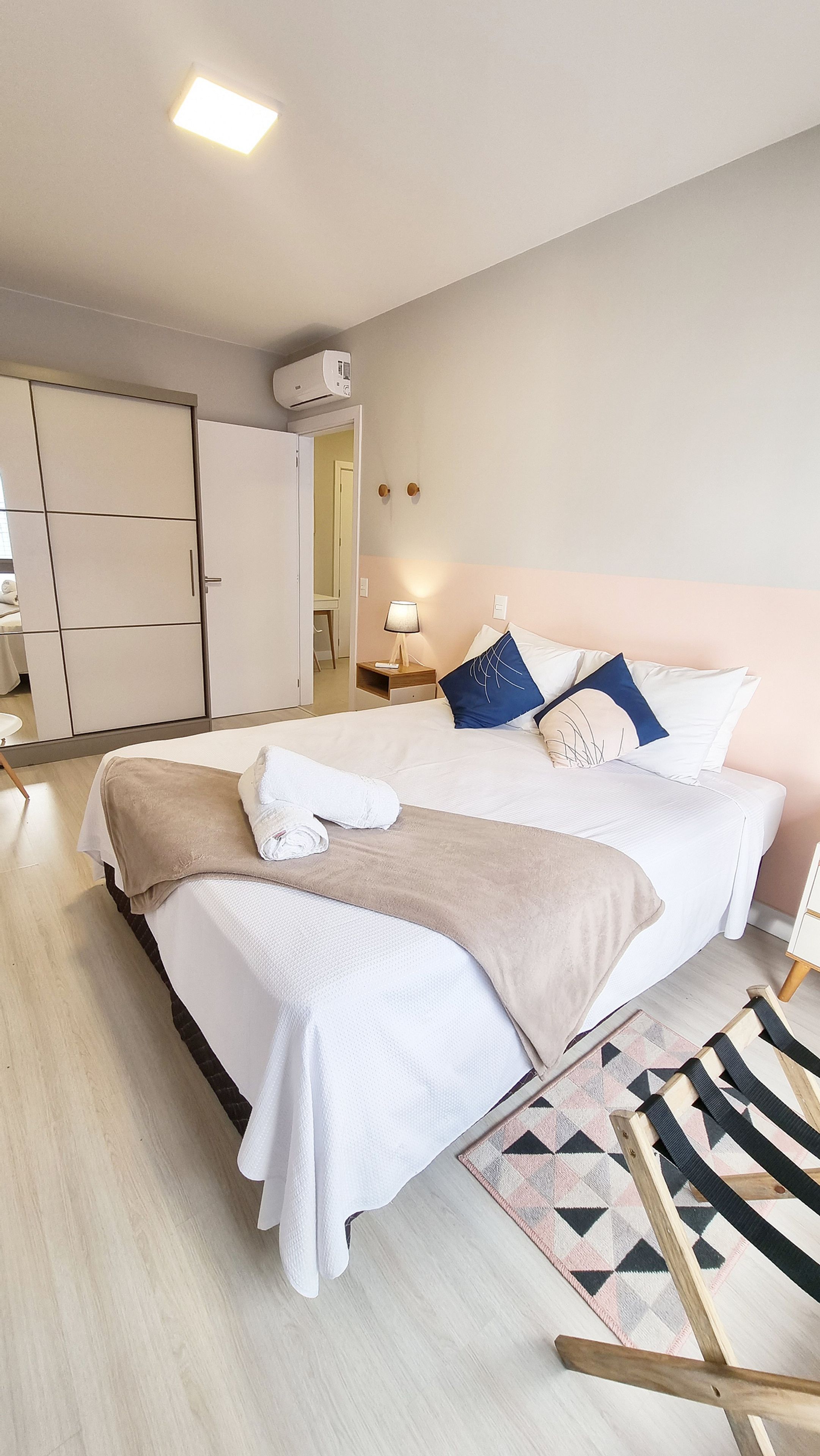 A neatly arranged bedroom with a bed, bedside tables, a lamp, and a wardrobe.