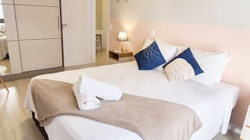 A neatly arranged bedroom with a bed, bedside tables, a lamp, and a wardrobe.
