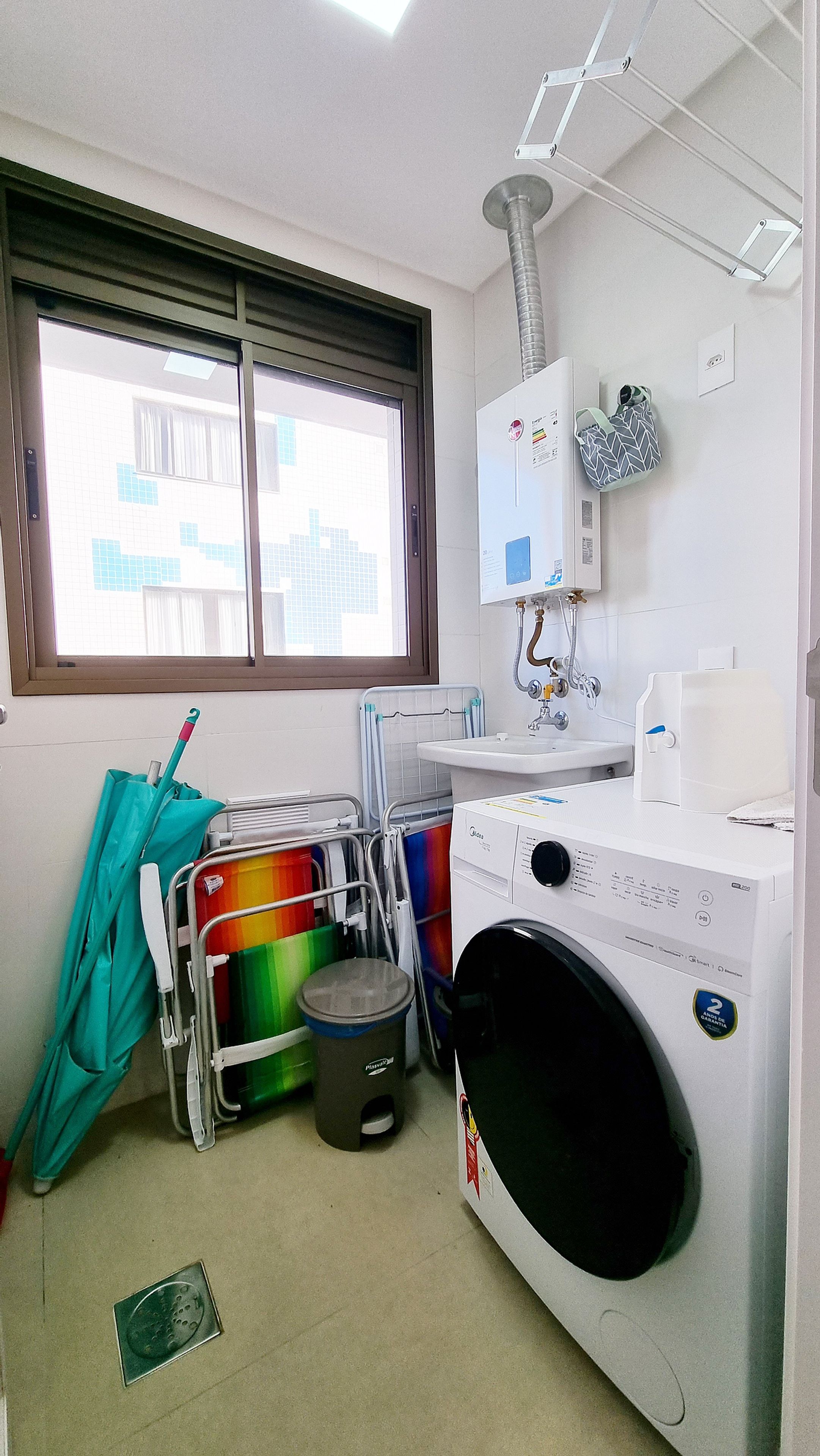 A laundry room with a washing machine, a sink, a window, and a radiator.