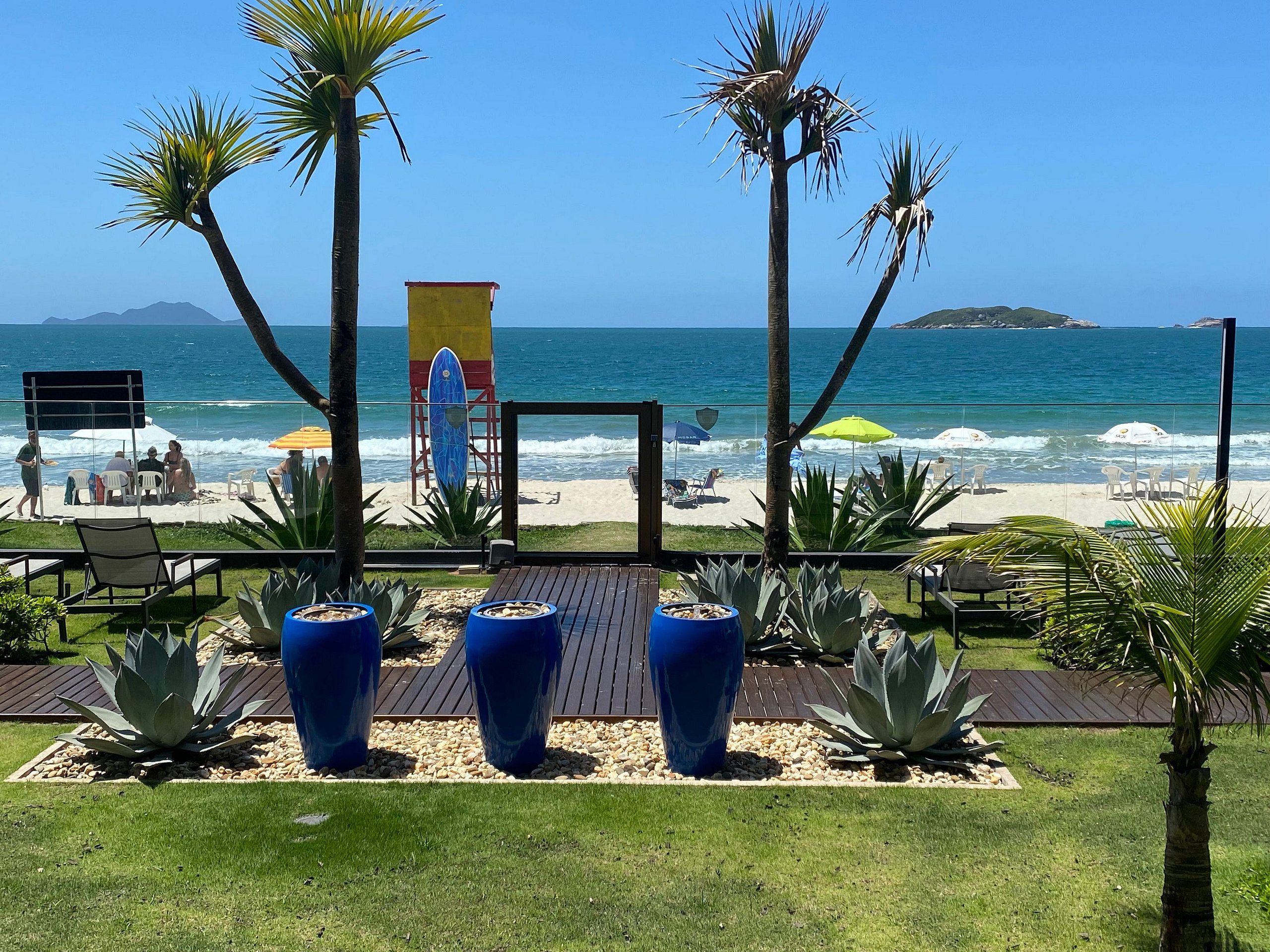 A beachside patio with seating, a surfboard display, and a view of the ocean.