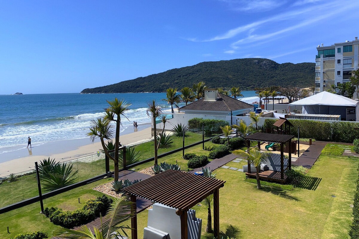Ein Hotel an der Küste mit Blick auf den Strand, einem Poolbereich und einer Bergkulisse.