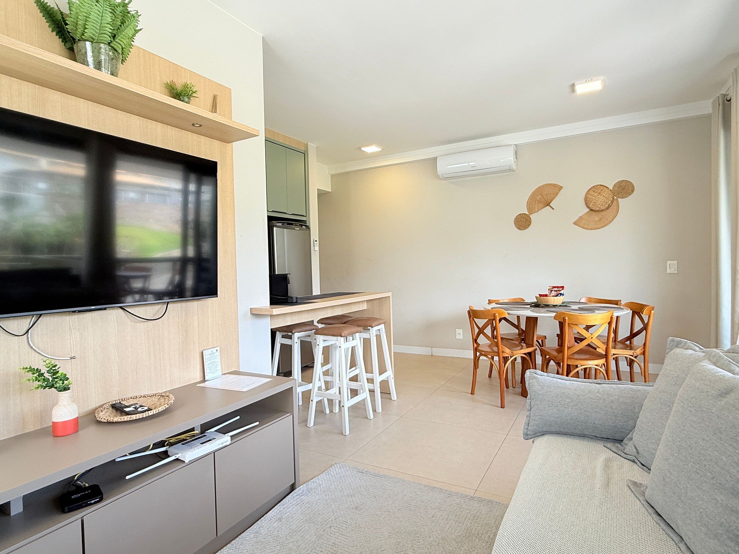 Une cuisine moderne équipée d’un téléviseur à écran plat, d’un coin repas avec des chaises en bois et d’un canapé.