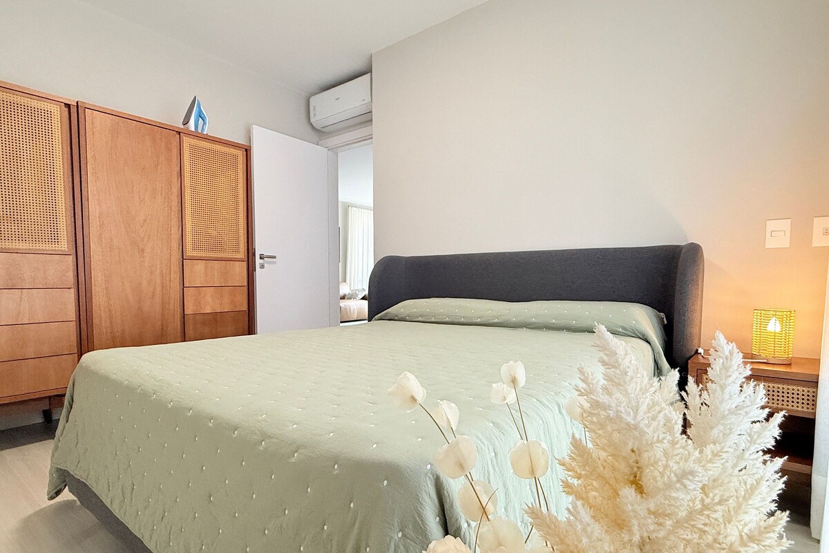 Une chambre à coucher comprenant un lit, une armoire, une table de chevet avec une lampe et un climatiseur fixé au mur.