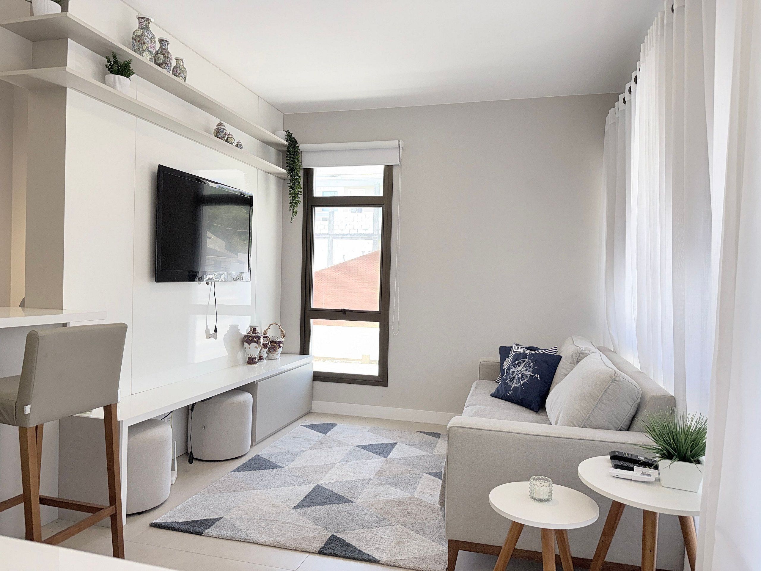 Un espace de vie compact comprenant un coin cuisine, un canapé, un téléviseur et une petite table agrémentée d’une plante.