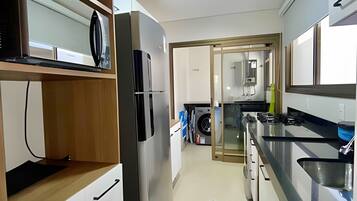 Een moderne keuken met een inbouwkoelkast, een wasmachine en een spoelbak.