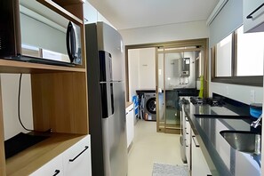 Een moderne keuken met een inbouwkoelkast, een wasmachine en een spoelbak.