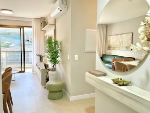 A modern hotel room with a balcony, a dining area, and a living space with a large mirror and artwork. - Res Belvedere Beach Garden (Florianópolis)
