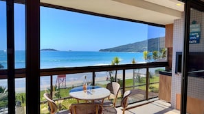A balcony with a view of the sea, a table with chairs, and a sign with text.