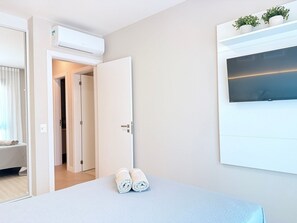 Une chambre d’hôtel équipée d’un lit, d’une télévision, d’un climatiseur, d’une porte et d’une fenêtre avec des plantes.
