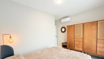 A bedroom with a bed, a wardrobe, a bedside lamp, and an air conditioning unit.
