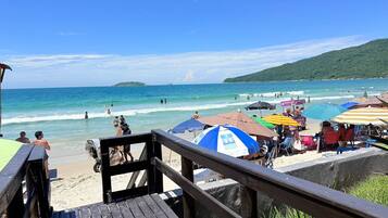 Na praia, areia branca, espreguiçadeiras, guarda-sóis