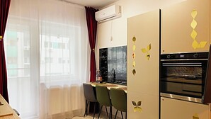 Una cucina moderna con forno a incasso, zona pranzo con sedie e finestra con tende leggere.