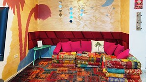 Una stanza con un letto, trapuntoni colorati, un affresco, un lampadario e un poster a tema marocchino.