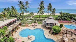 A resort with a large pool, palm trees, and a beach view. - Resort beach condo w beach service /601 (Miami Beach)