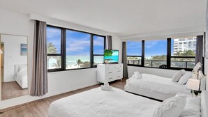 A modern hotel room with two beds, a TV, and large windows with a beach view. - Resort beach condo w beach service /601 (Miami Beach)
