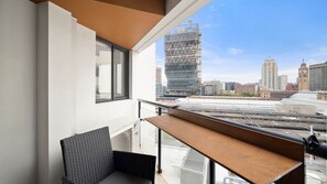 Ein Balkon mit Blick auf eine Stadtansicht, darunter ein markantes, modernes Gebäude im Bau.