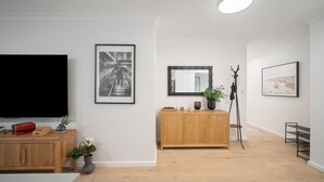 Un salon moderne doté d’un téléviseur à écran plat, d’un meuble en bois et d’un grand miroir.