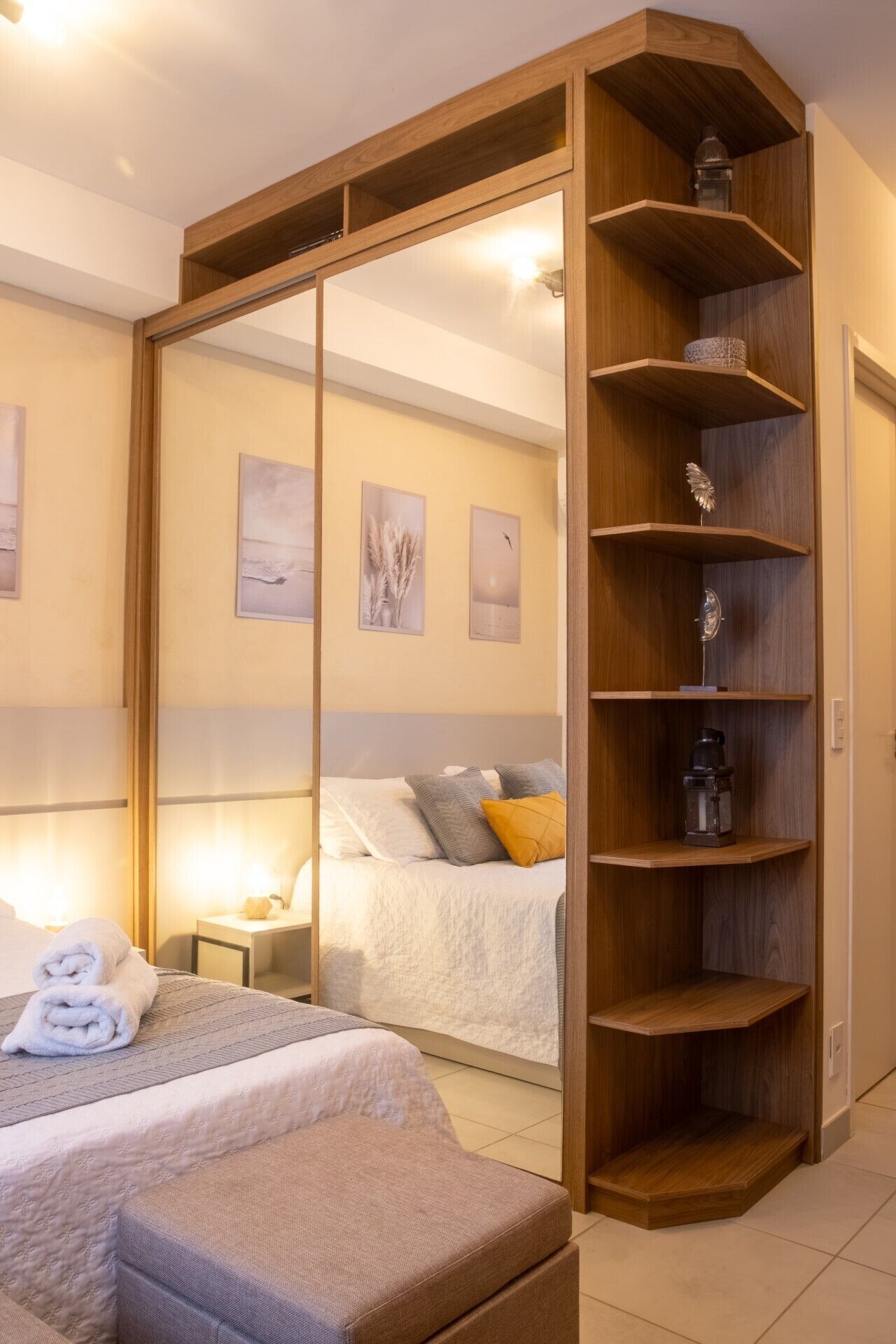 Una camera da letto con un letto, un comodino, un'armadiatura in legno con ripiani e uno specchio.