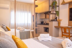 Ein Hotelzimmer mit Bett, Schreibtisch, Küchenzeile und Bad.