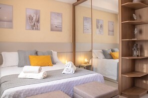 A hotel room with a large bed, a bedside table with a lamp, a mirror, and artwork on the walls. - Studio Zen - Vila Olímpia (São Paulo)