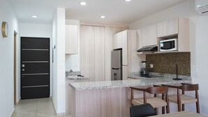 A modern kitchen with a central island, built-in appliances, and a microwave above the counter. - Almarena (Mazatlán)