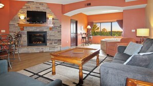 A living room with a stone fireplace, a flat-screen TV, a pool table, and a sofa. - River View Condo - Top Floor - Resort Pools - Pet Friendly! (Wisconsin Dells)