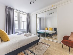 Ein Schlafzimmer mit Bett, Stuhl, Spiegel und Kleiderschrank.