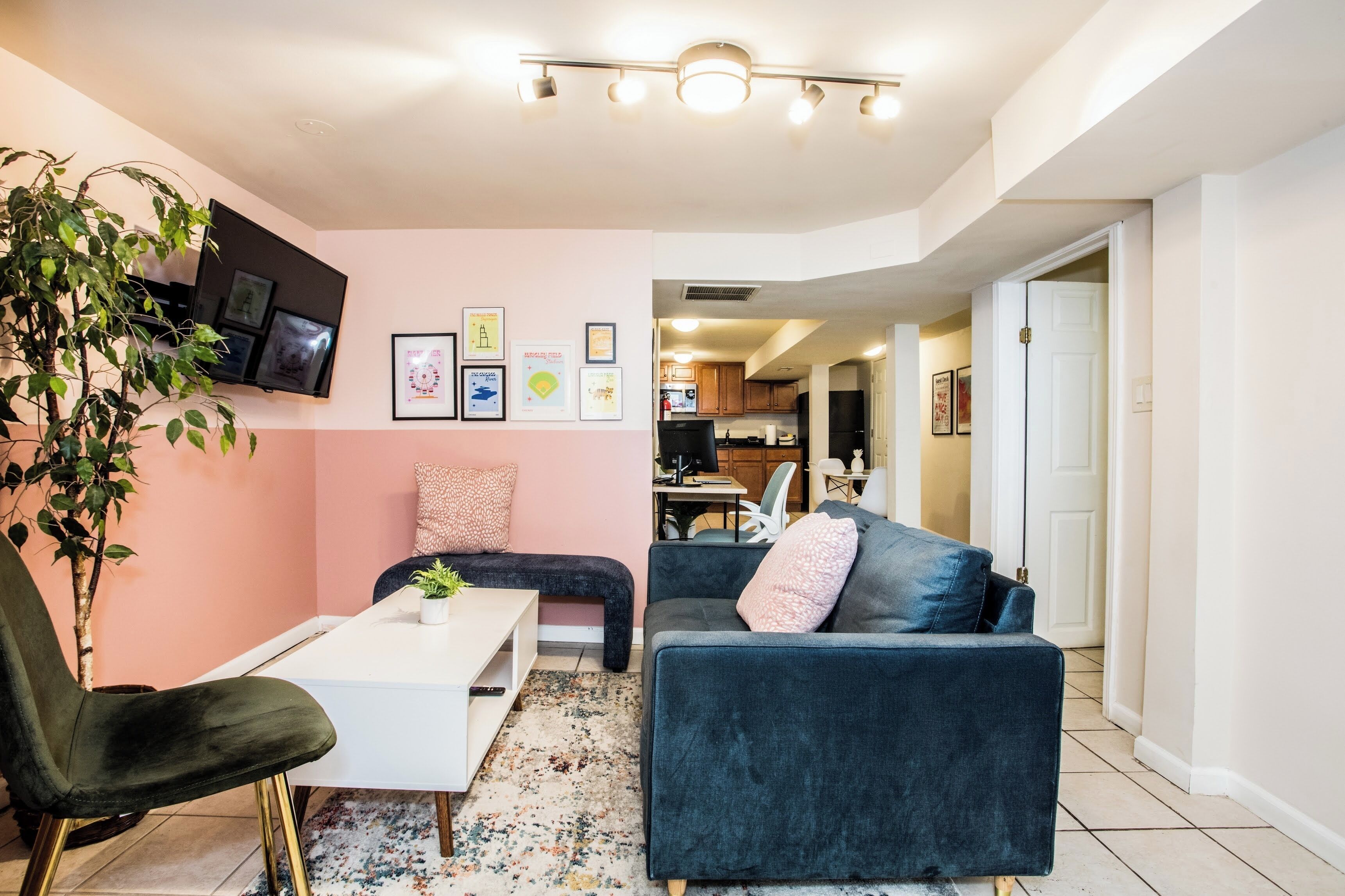 Un salon avec un canapé, un fauteuil, une table basse, un téléviseur et une plante.