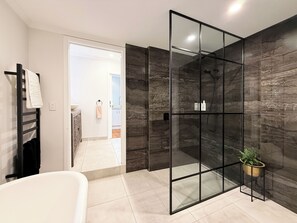 Ein modernes Badezimmer mit Duschkabine aus Glas, einer weißen Badewanne und einem Blumentopf.